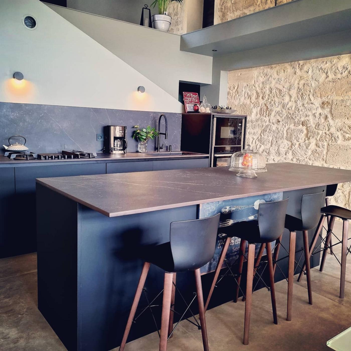 Spacieuse cuisine avec mur en pierres et poutres apparentes